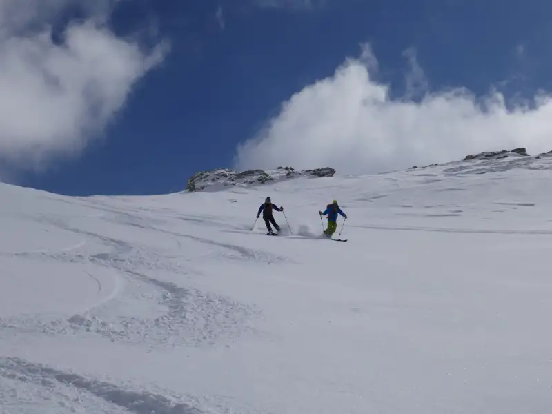 Zwei Skifahrer in Aktion auf einem schneebedeckten Hang.