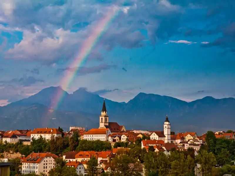 Stadtansicht mit Bergen und Regenbogen.