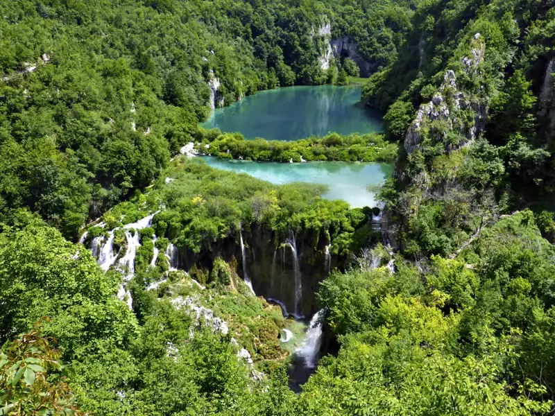 Sicht auf die kaskadenförmig angeordneten Seen und Wasserfälle, umgeben von üppigem Grün.
