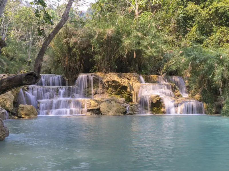 Wasserfall mit mehreren Kaskaden und türkisfarbenem Becken inmitten tropischer Vegetation.