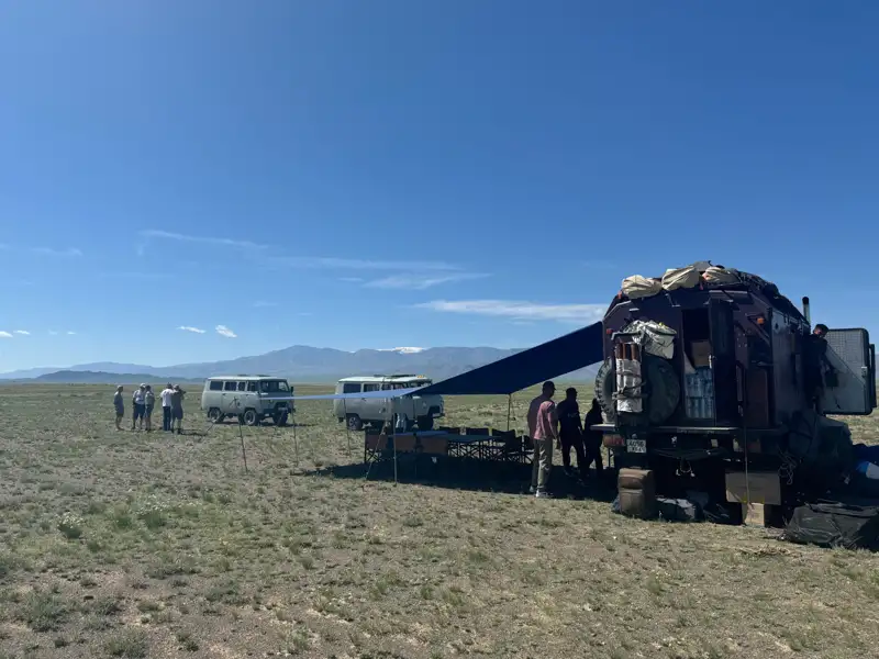 Reisegruppe während einer Pause mit Fahrzeugen und Lager.