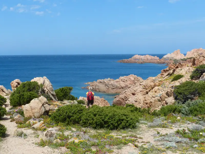 Wanderer auf einem Küstenpfad mit Blick auf das Meer und die Felsen.