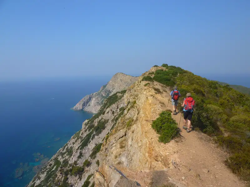 Wanderer auf einem Küstenpfad mit Meerblick.