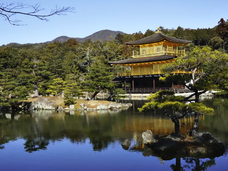 Der Goldene Pavillon (Kinkaku-ji) in Kyoto, Japan, mit seiner goldenen Fassade, die sich im umliegenden Teich spiegelt.