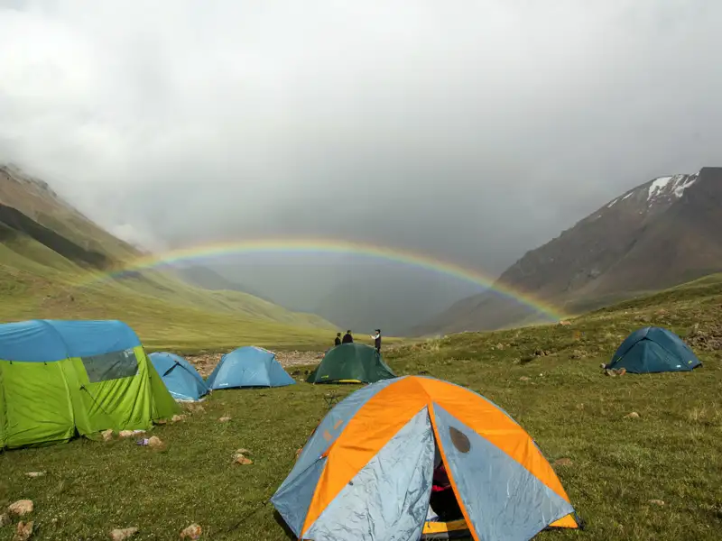 Campingplatz in den Bergen mit Regenbogen