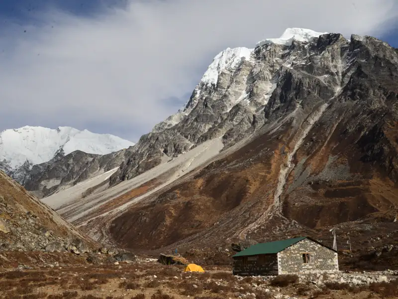 Eine einfache Berghütte und ein Zelt bieten Schutz während des Trekkings im Himalaya.