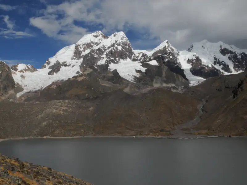 Bergsee mit schneebedeckten Bergen im Hintergrund.