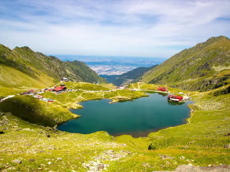 Blick auf den Balea See mit seinen Berghütten und der umliegenden Berglandschaft.