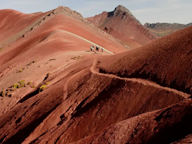 Wanderer auf einem Bergpfad mit roter Erde.