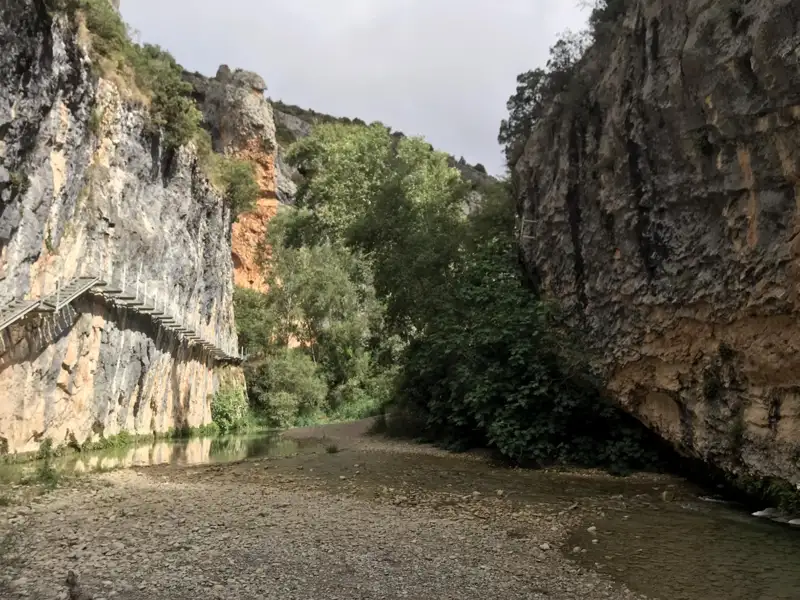 Wanderweg mit Stufen in einer Schlucht entlang eines Flusses.