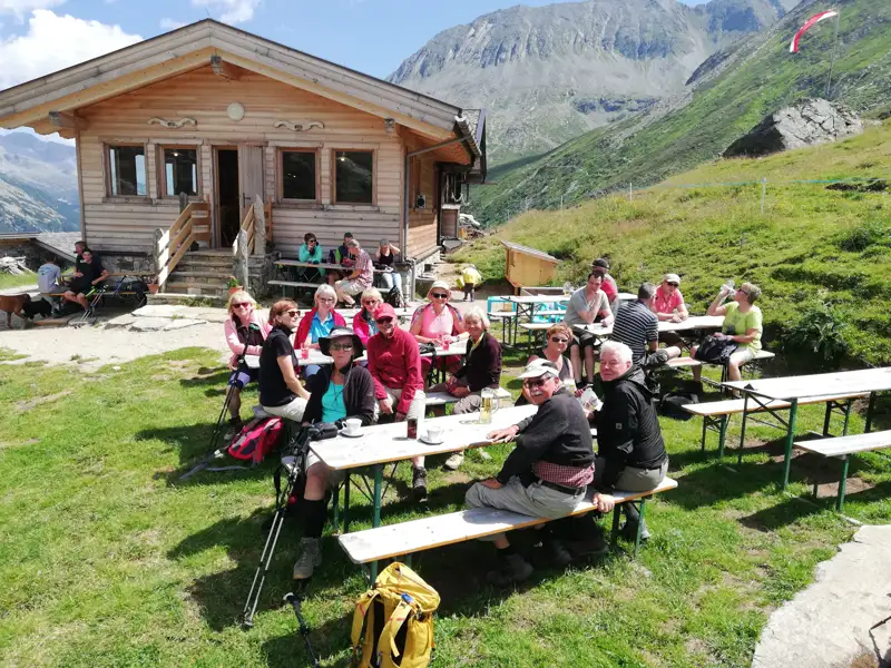 Türkisfarbener See in den Bergen mit einem roten Haus am Ufer.