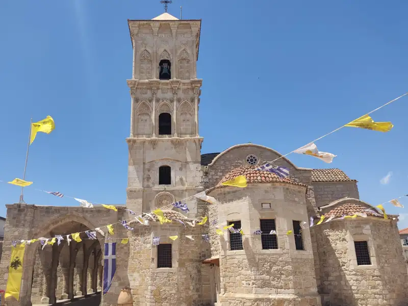 Steinkirche mit Glockenturm und Fahnen.