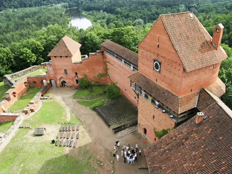 Luftbild einer Backsteinburg mit Innenhof, Besuchern und umliegender Landschaft.