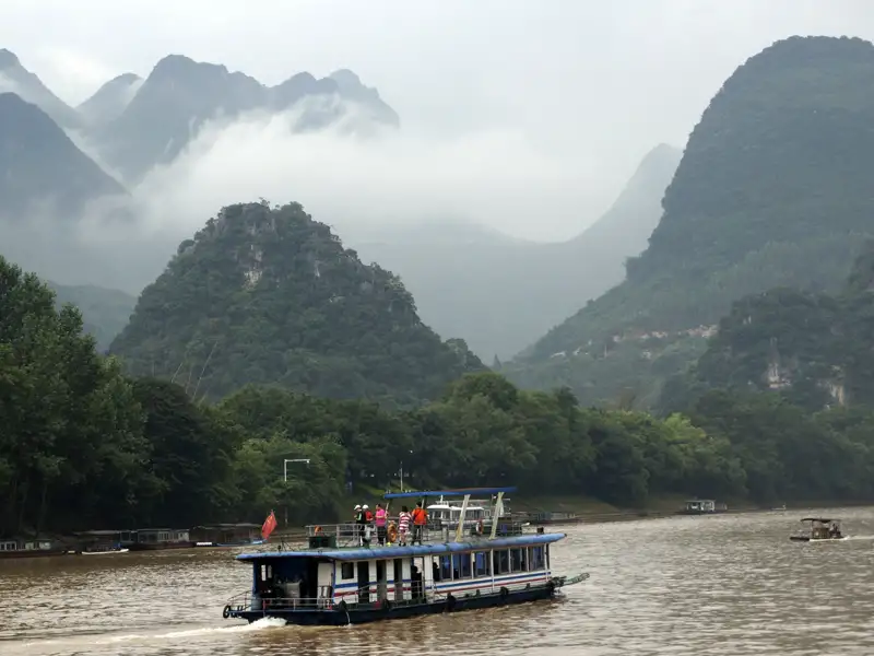 Ausflugsboot auf Flussfahrt inmitten einer Berglandschaft.