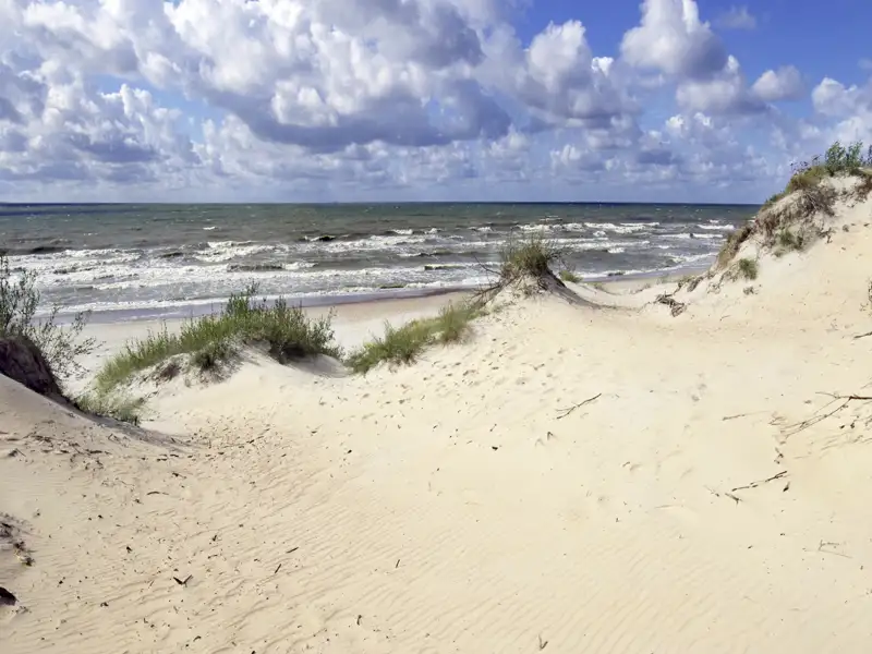 Dünen und Meer unter bewölktem Himmel.
