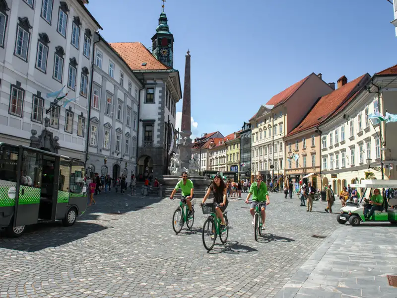 Radfahrer auf dem Platz in Ljubljana. Im Hintergrund sind historische Gebäude zu sehen.