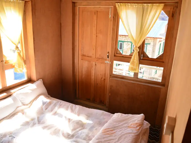 Innenansicht eines Zimmers mit Bett und Fenster.