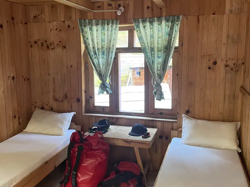 Unterkunft auf der Reise: Ein einfaches Zimmer mit zwei Betten und bereitgestelltem Gepäck.