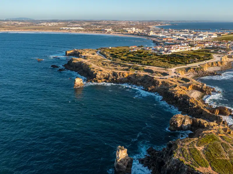 Luftbild einer felsigen Küste mit Blick auf die Stadt und das Meer.