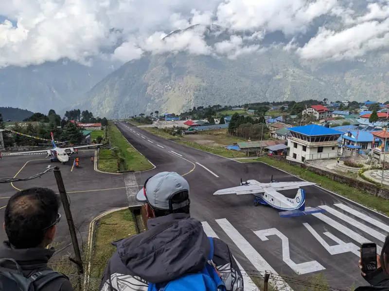 Flugzeug auf der Landebahn des Flughafens Lukla, umgeben von Bergen.