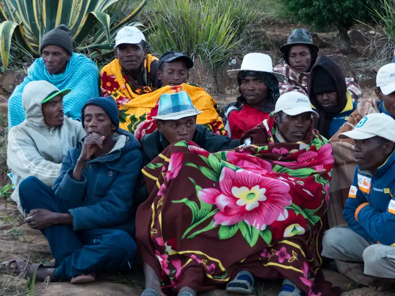 Gruppe von Menschen, die in Decken und Hüten versammelt sind.
