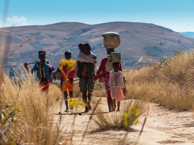 Familie auf Wanderschaft durch hügelige Landschaft.