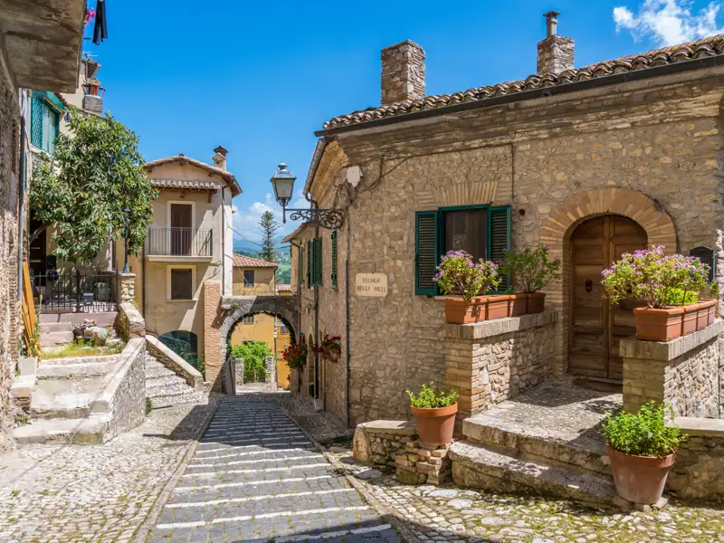 Traditionelle Steinhäuser und Kopfsteinpflastergasse in einem italienischen Dorf.