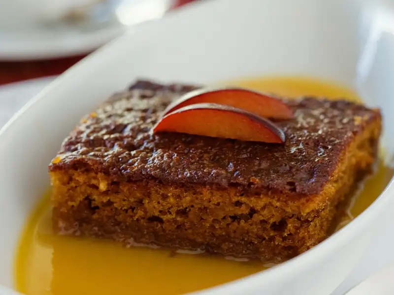 Kuchenstück mit Pflaumen und Soße.