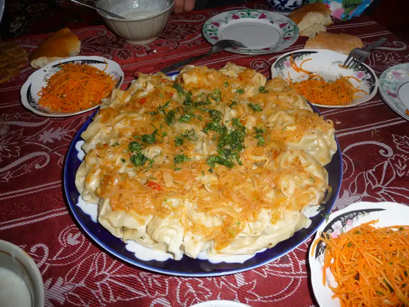 Manty mit Zwiebeln und Kräutern, serviert mit Karottensalat.