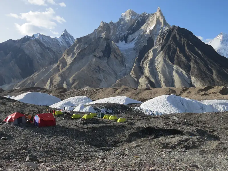 Basislager mit Zelten in einer hochalpinen Umgebung, umgeben von Gletschern und Bergen.