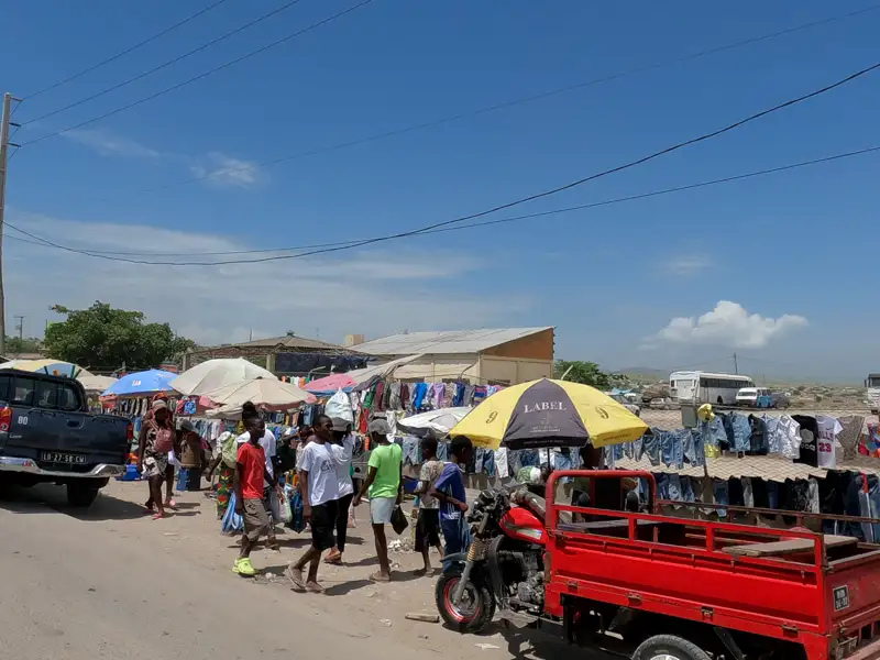 Lokaler Markt mit Händlern, die Waren unter Sonnenschirmen verkaufen.