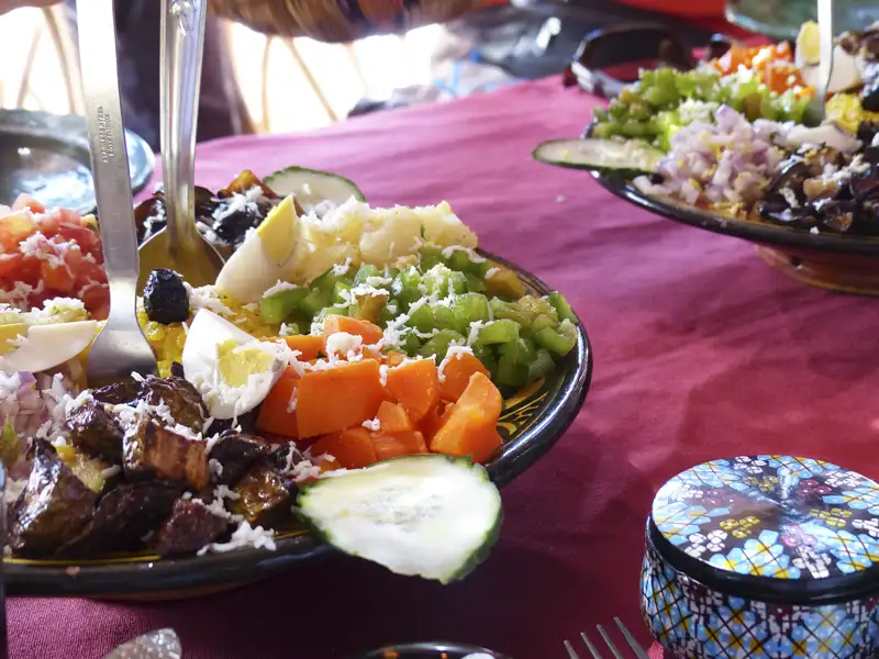 Bunter marokkanischer Salat mit verschiedenen Gemüsesorten, Eiern und Oliven, serviert auf einem traditionellen Teller.