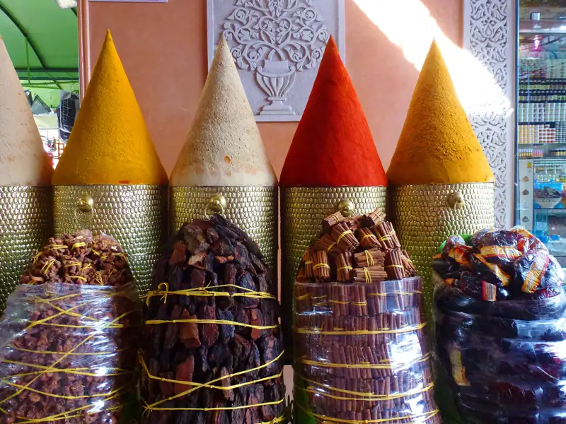 Verschiedene Gewürze wie Kurkuma, Paprika und Zimt, ausgestellt auf einem Markt.