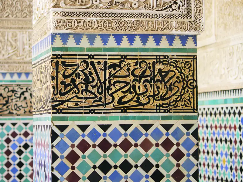 Nahaufnahme der kunstvollen Fliesen und Kalligrafie an einer Säule, die die detailreiche Gestaltung der Architektur zeigt.