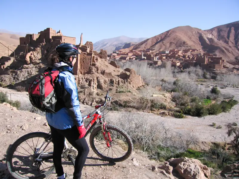 Mountainbikerin mit Blick auf historische Stätte im Tal während einer Radtour.