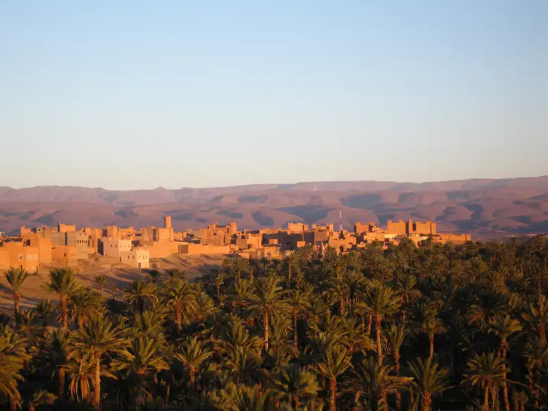 Traditionelle Lehmbausiedlung inmitten einer Oase mit Palmen.