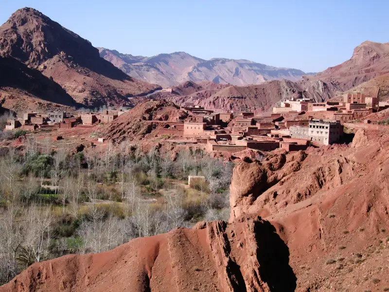 Lehmhäuser eines Berberdorfes im Atlasgebirge, umgeben von roter Felslandschaft.