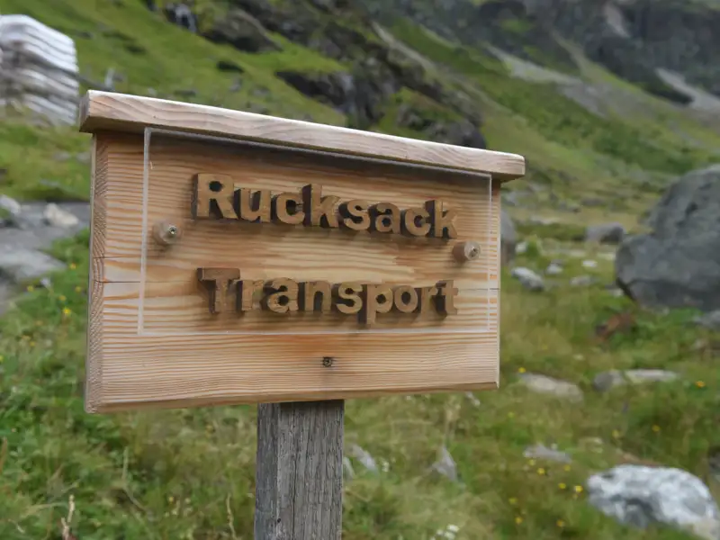 Schild für Rucksacktransport auf einer Wanderroute.