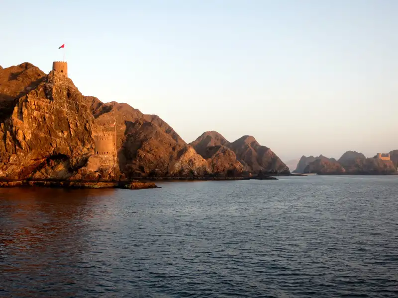 Felsige Küste Omans mit Festung und Flagge.