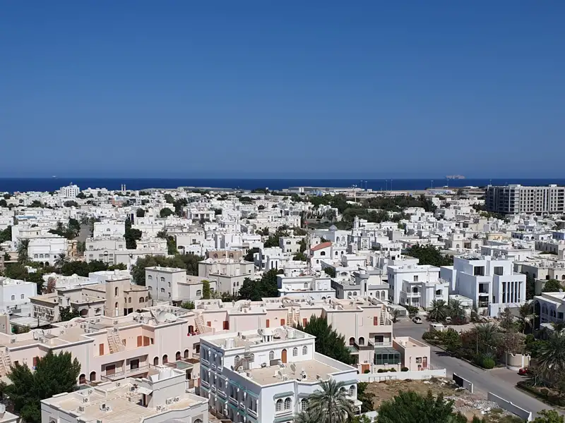 Panoramablick auf die Stadt mit weißen Gebäuden und dem blauen Meer im Hintergrund.