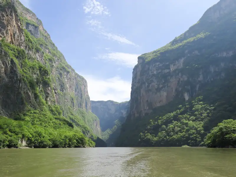 Flussfahrt durch eine Schlucht mit hohen, bewaldeten Wänden.