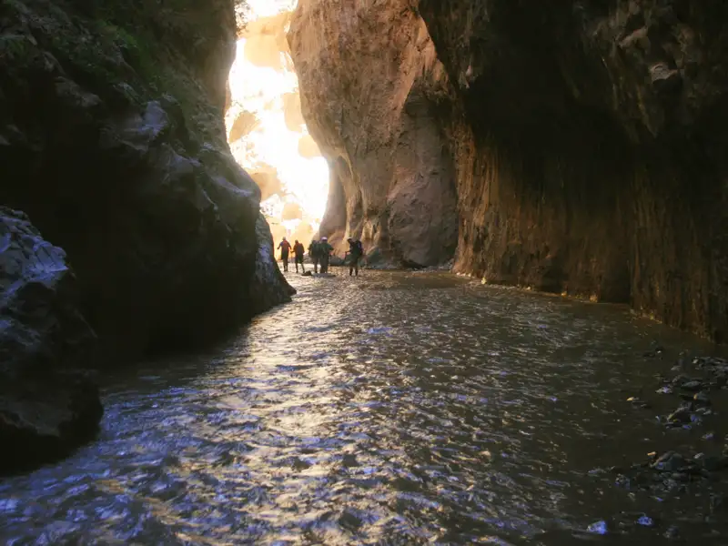 Wanderer durchqueren eine wasserführende Schlucht.