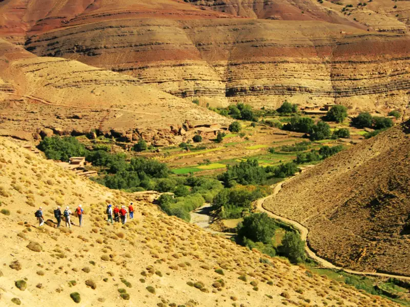 Wandergruppe auf einem Bergpfad in einer trockenen Gebirgslandschaft.