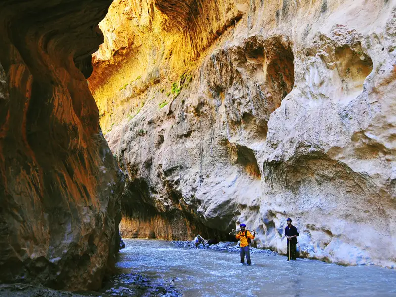 Wanderer durchqueren eine Schlucht mit einem Fluss.