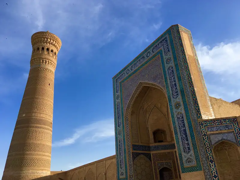 Minarett und kunstvoll verzierter Eingang eines historischen Gebäudes.