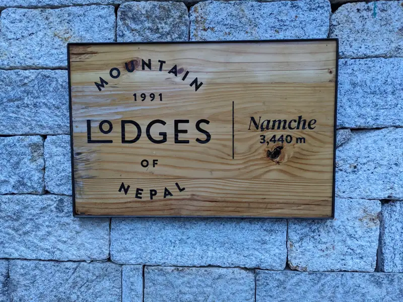 Schild der Mountain Lodges of Nepal in Namche, das die Unterkunft und die Höhe von 3.440 m angibt.