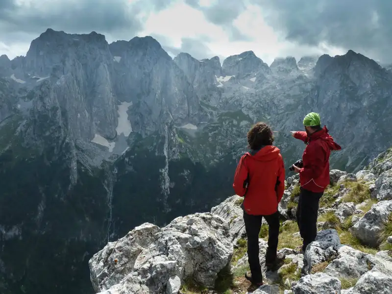 Zwei Wanderer auf einem Berggipfel mit Blick auf das Tal.