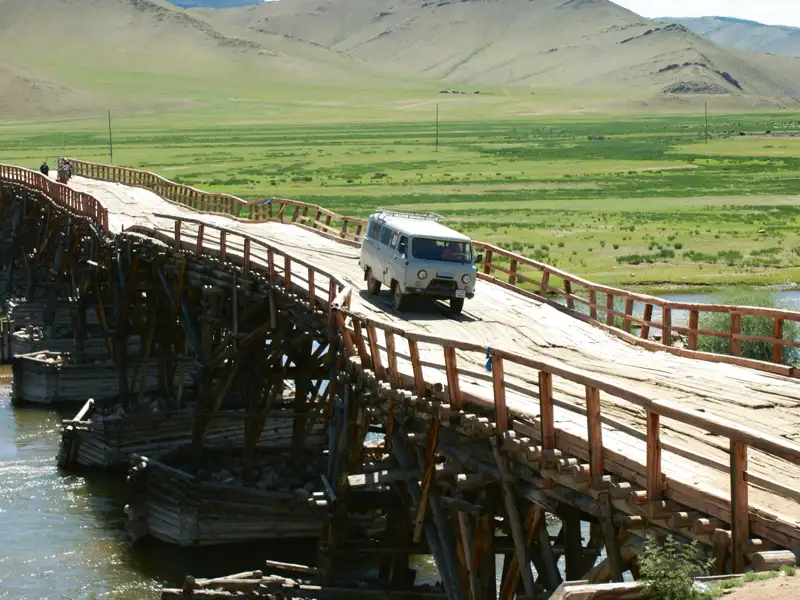 Reisefahrzeug überquert eine hölzerne Brücke.