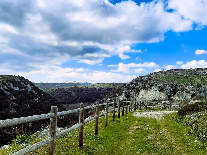 Wanderweg mit Holzgeländer und Aussicht auf die umliegende Landschaft.