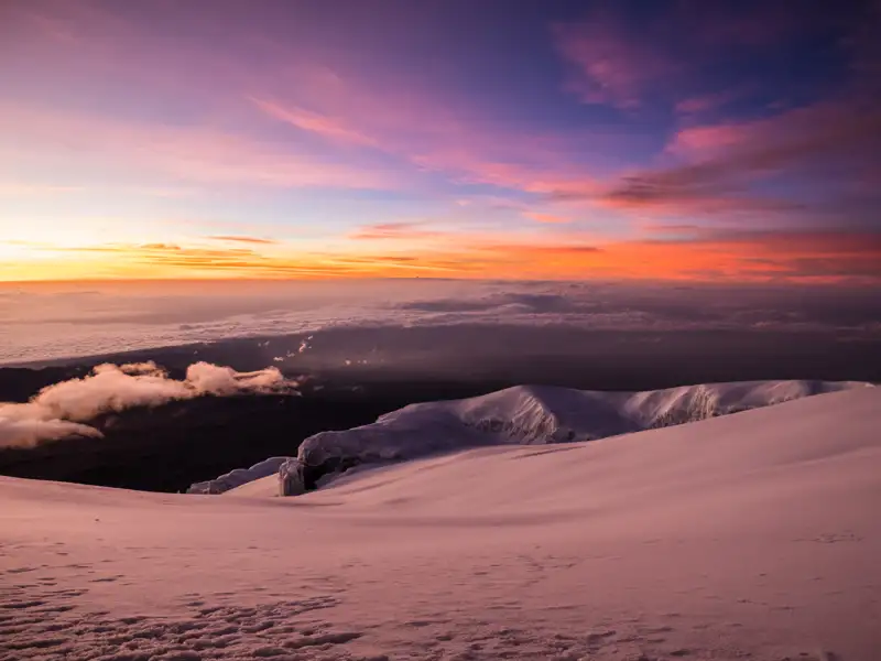 Sonnenaufgang über einer verschneiten Berglandschaft.